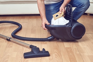 A woman empties a vacuum cleaner.