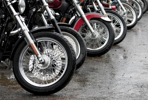 A row of parked motorcycles showing the front tires.