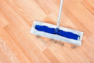 Swiffer sweeping up dirt and debris off of a wood floor.