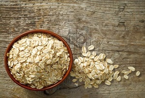 A small bowl of oats with a pile of oats beside it.