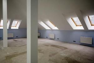 Two columns in an attic with windows in the roof and an unfinished floor.