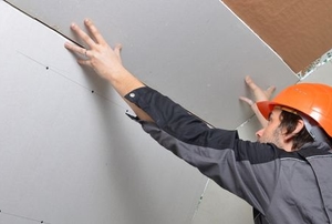 Person installing drywall on a ceiling