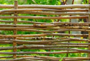 A handmade log and twig fence in the garden.