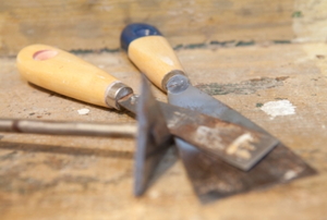 A putty knife and chisel used to remove masonry paint.