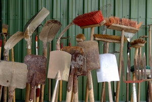 A grouping of outdoor tools against a green shed.