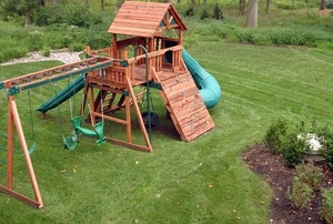 A cedar swing set in a backyard.