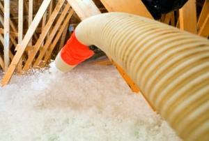 Blowing insulation into an attic from the perspective of the installer.