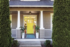 Front porch with railing, yellow door, rug, and potted plants