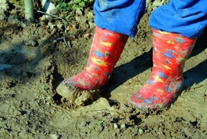 Red kid boots in wet, clay soil.