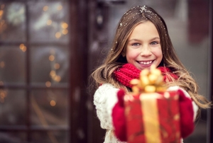 A young girl holding a red present.