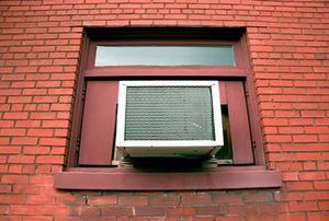 Air conditioner sitting in window, surrounded by brick