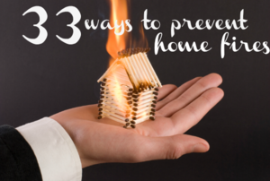 A hand holding a house made of matchsticks that are on fire.