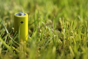 A yellow rechargeable battery sits in the grass.