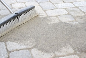 brush moving paver sand into walkway