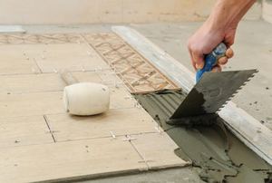 Someone applying thinset to a subfloor for tile.