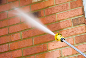 Spraying a brick wall with water from a hose