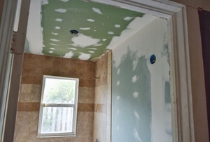 A bathroom under construction with greenboard and drywall mud.