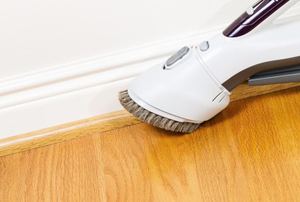 White baseboards against a tan wall and wood flooring.