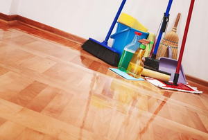 A pile of cleaning supplies on a shiny wood floor. 