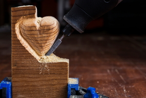 A Dremel tool carving a heart out of a piece of wood.