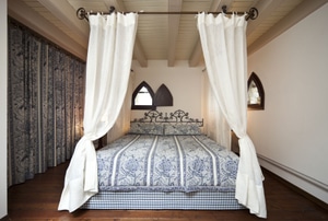 Bed with blue comforter and white canopy curtains.