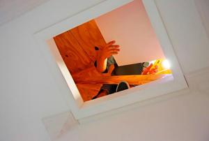 Looking up through an attic entrance to where a contractor is working.