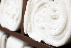 wooden towel rack with white rolled up towels