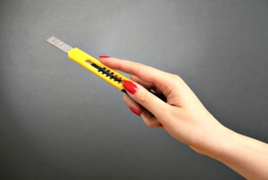 A woman holds a utility knife.