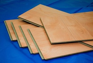 Slats of laminate flooring laying in a pile on a blue cloth.