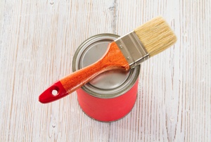 A paintbrush on top of a can of lacquer finish.