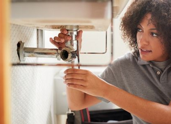 woman fixing pipe under sink