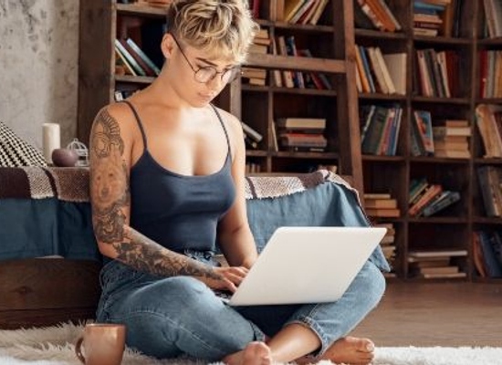 woman working second job on a computer in a room with bookshelves