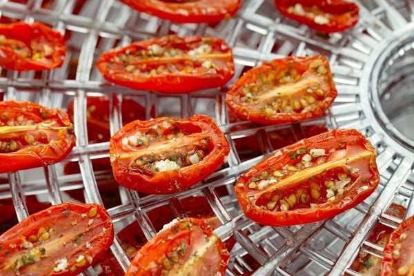 A food dehydrator with tomatoes on it. 