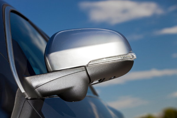 A car side mirror against a blue sky. 