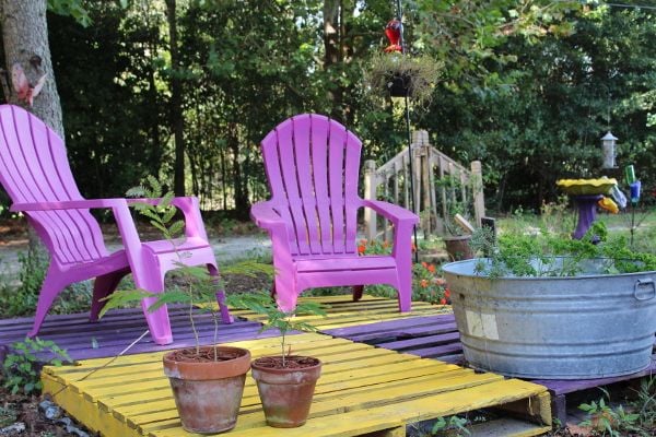 A deck of painted pallets with adirondack chairs. 