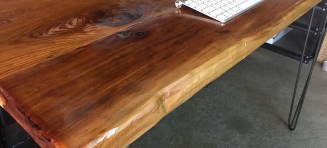 A keyboard and monitor sitting on a handmade looking wood tabletop with rounded metal legs