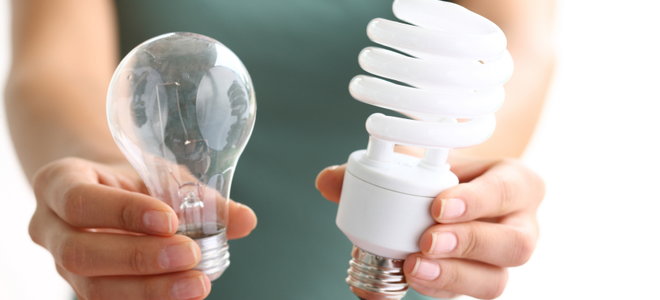 A woman holding two different light bulbs. 