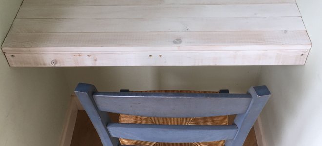 A wood floating desk with a blue chair in front of it.