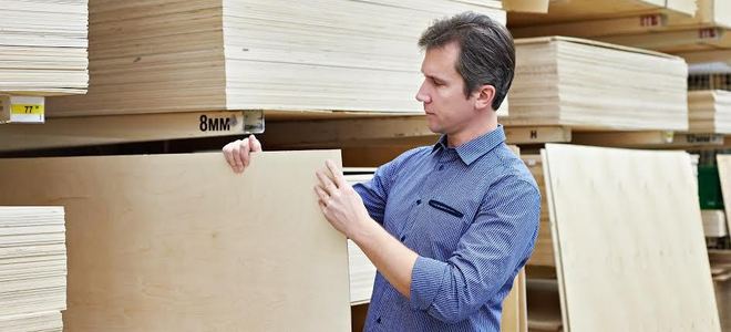 A man shopping for plywood in a home improvement store.
