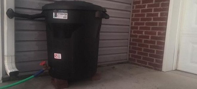 A rain barrel outside a garage.