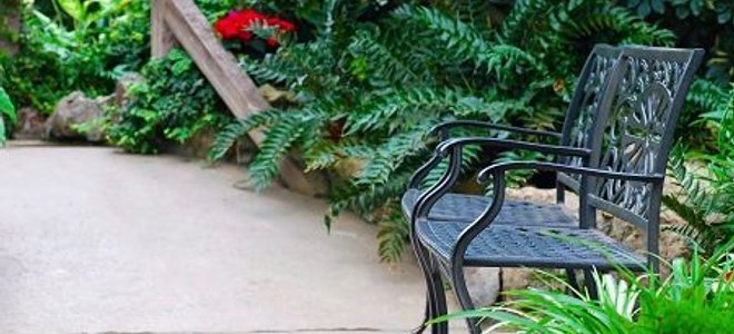 A concrete patio with wrought-iron metal chairs.