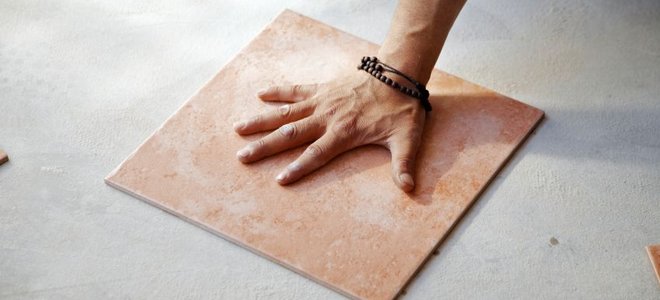 a hand pressing a tile down on the ground