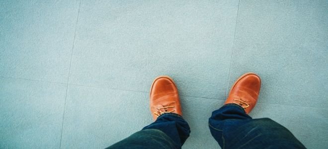 A pair of brown men’s shoes on a blue tile floor.