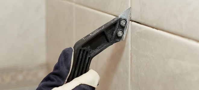 A grout saw cleaning out grout from between shower tile. 