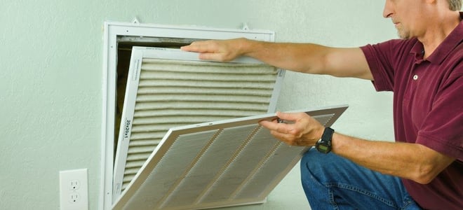 A man removing an air conditioner filter. 