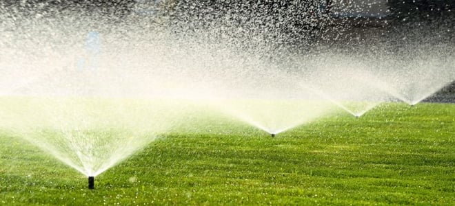 A series of sprinklers spraying water on a lawn. 