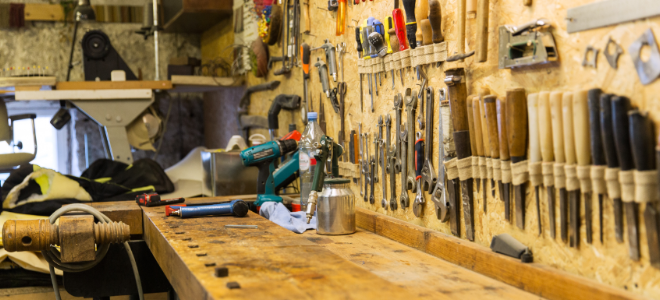 a workbench with a wall full of tools above it