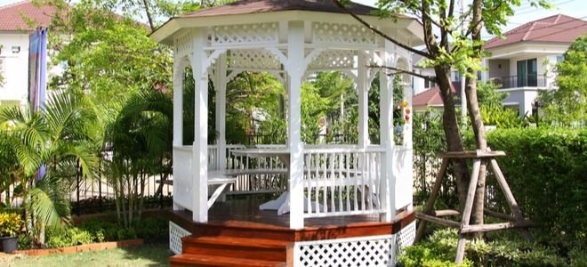 octagon gazebo in backyard with bushes