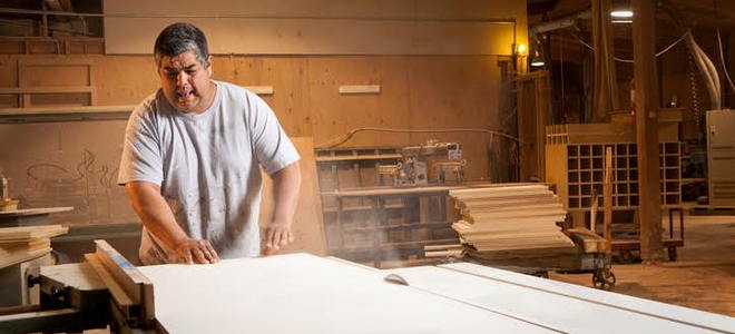 man cutting a sheet of plywood