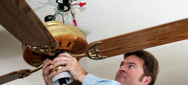 man working on a ceiling fan fixture